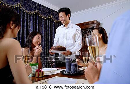 Friends at dining table, man giving cake to woman View Large Photo Image Stock Photo - Friends at dining table, man giving cake to woman. Fotosearch