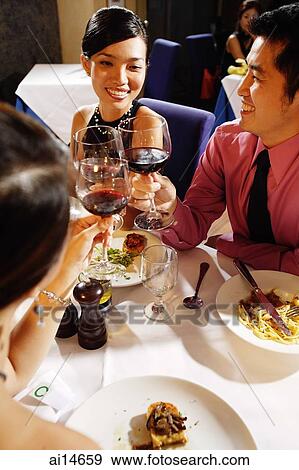 Friends in restaurant raising wine glasses for a toast View Large Photo Image Stock Photo - Friends in restaurant raising wine glasses for a toast. Fotosearch