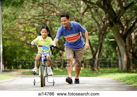Girl cycling, father running behind her View Large Photo Image Stock Photograph - Girl cycling, father running behind her. Fotosearch