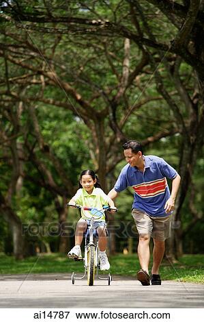 Girl cycling, father running next to her View Large Photo Image Stock Photo - Girl cycling, father running next to her. Fotosearch