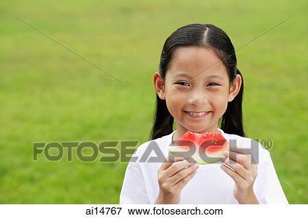Girl holding slice of watermelon, smiling View Large Photo Image Stock Photo - Girl holding slice of watermelon, smiling. Fotosearch