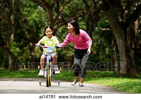 Girl on bicycle, mother walking next to her View Large Photo Image Stock Image - Girl on bicycle, mother walking next to her. Fotosearch