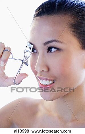 Headshot of woman using eyelash curler View Large Photo Image Stock Photo - Headshot of woman using eyelash curler. Fotosearch