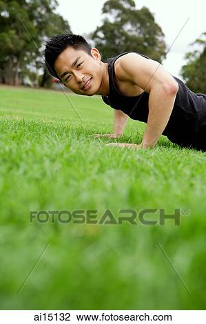 Man doing push-ups on grass, looking at camera View Large Photo Image Stock Image - Man doing push-ups on grass, looking at camera. Fotosearch