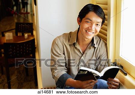 Stock Image - Man holding book, smiling. Fotosearch