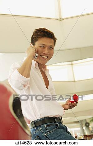 Man holding ring box, using mobile phone, looking away View Large Photo Image Stock Photo - Man holding ring box, using mobile phone, looking away. Fotosearch
