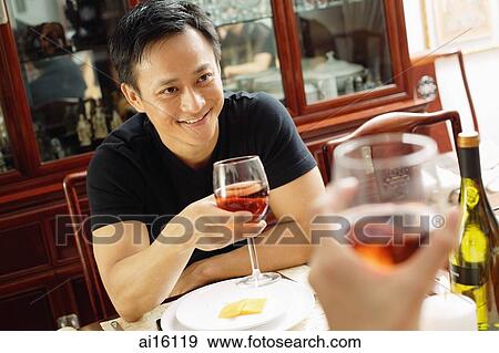 Man holding wine glass, smiling at person across from him View Large Photo Image Stock Photo - Man holding wine glass, smiling at person across from him. Fotosearch
