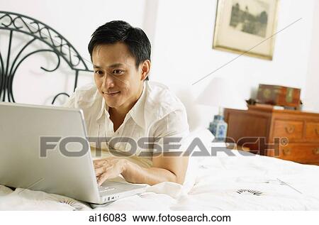 Man in bedroom, using laptop View Large Photo Image Stock Image - Man in bedroom, using laptop. Fotosearch