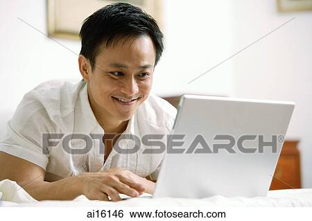 Man in bedroom, using laptop View Large Photo Image Stock Photograph - Man in bedroom, using laptop. Fotosearch