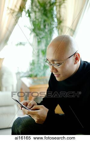 Man in black turtleneck, holding mobile phone, text messaging View Large Photo Image Stock Photography - Man in black turtleneck, holding mobile phone, text messaging. Fotosearch