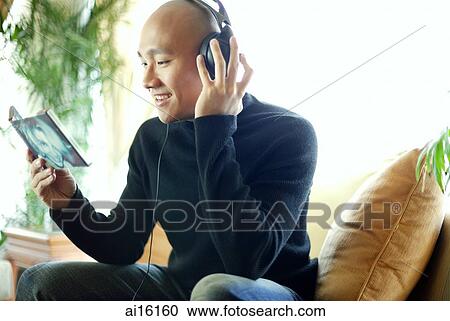 Stock Image - Man in black turtleneck, with headphones, listening to music. Fotosearch