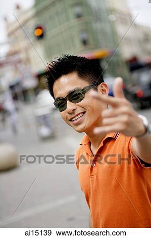 Stock Photo - Man in sunglasses, looking at camera, making hand sign. Fotosearch