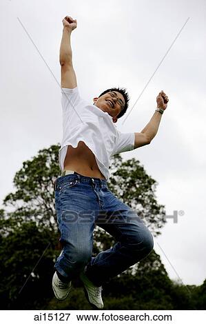 Stock Photo - Man jumping in air, both arms raised, making fist. Fotosearch