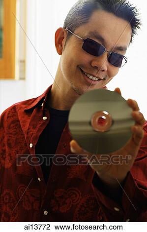 Man looking at camera, holding CD View Large Photo Image Stock Image - Man looking at camera, holding CD. Fotosearch