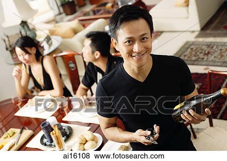 Man looking at camera, holding wine bottle, people in the background View Large Photo Image Stock Photo - Man looking at camera, holding wine bottle, people in the background. Fotosearch