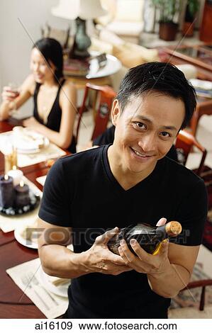 Stock Photo - Man looking at camera, holding wine bottle. Fotosearch