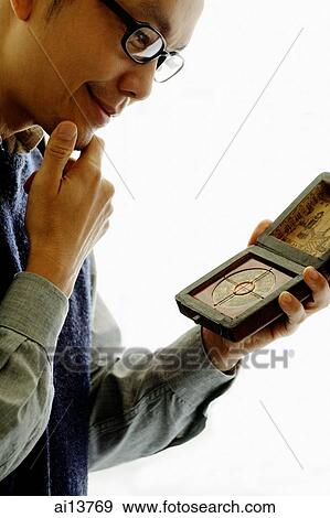 Man looking down at Chinese compass, hand on chin View Large Photo Image Stock Photo - Man looking down at Chinese compass, hand on chin. Fotosearch