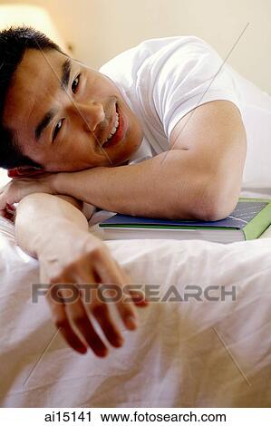 Man lying on arm, looking at camera, smiling View Large Photo Image Stock Image - Man lying on arm, looking at camera, smiling. Fotosearch