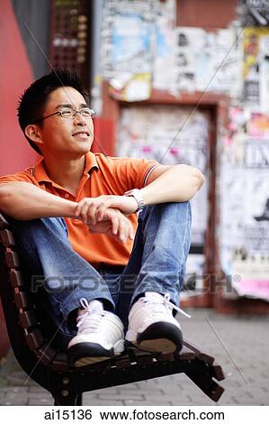 Stock Photograph - Man sitting on bench, looking away. Fotosearch