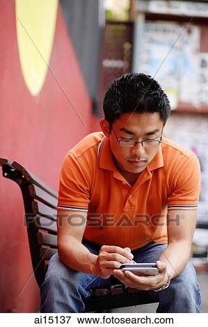 Man sitting on bench, using PDA View Large Photo Image Stock Photo - Man sitting on bench, using PDA. Fotosearch
