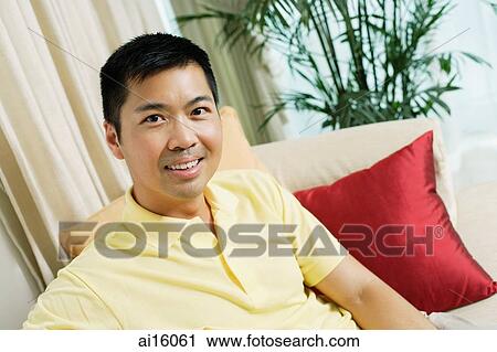 Man sitting on sofa, looking at camera View Large Photo Image Stock Image - Man sitting on sofa, looking at camera. Fotosearch