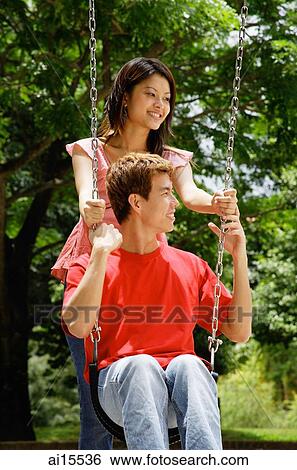 Man sitting on swing, woman standing behind him View Large Photo Image Stock Photograph - Man sitting on swing, woman standing behind him. Fotosearch