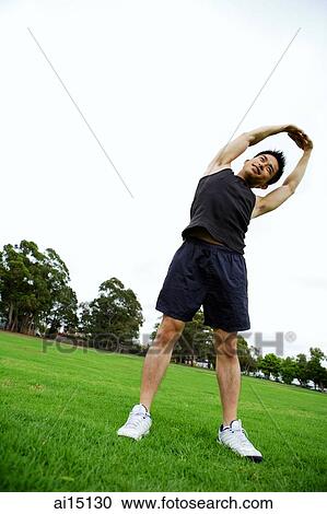 Man standing on grass, stretching View Large Photo Image Stock Image - Man standing on grass, stretching. Fotosearch
