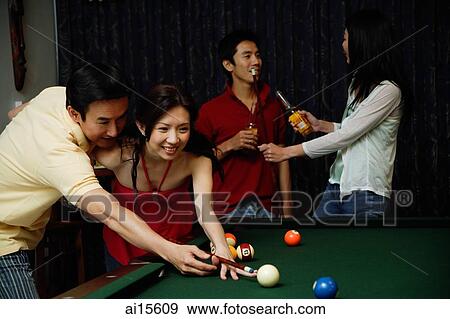 Stock Photo - Man teaching woman to play snooker, people in the background. Fotosearch