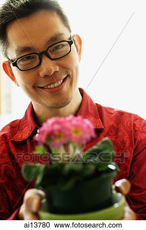 Man with glasses holding potted plant View Large Photo Image Stock Image - Man with glasses holding potted plant. Fotosearch