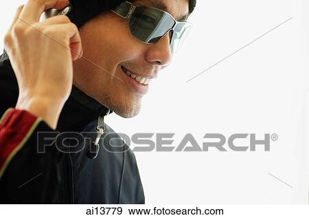 Stock Photo - Man with sunglasses, hand on headphones. Fotosearch