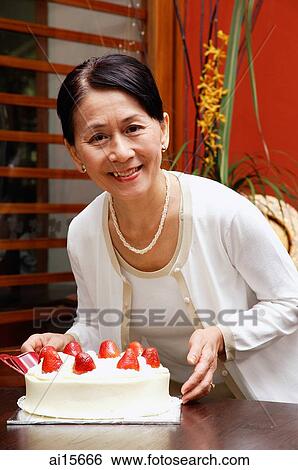 Mature woman holding birthday cake, looking at camera View Large Photo Image Stock Photograph - Mature woman holding birthday cake, looking at camera. Fotosearch