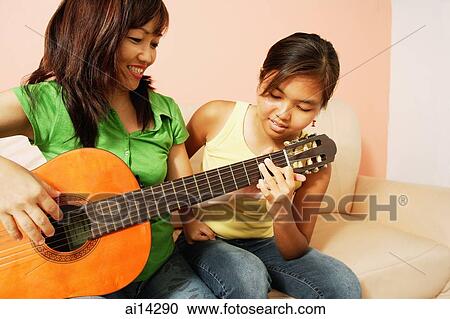 Mother and daughter side by side, mother holding guitar View Large Photo Image Stock Image - Mother and daughter side by side, mother holding guitar. Fotosearch