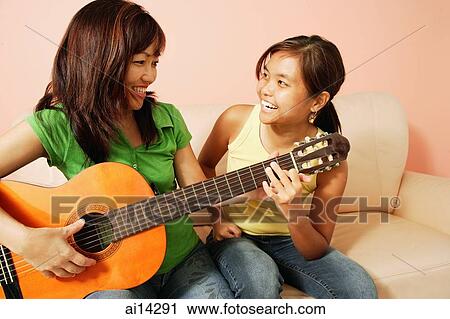 Mother and daughter side by side, holding guitar, looking at each other View Large Photo Image Stock Image - Mother and daughter side by side, holding guitar, looking at each other. Fotosearch