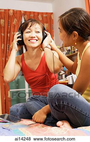 Mother and daughter side by side, mother listening to headphones View Large Photo Image Stock Photo - Mother and daughter side by side, mother listening to headphones. Fotosearch