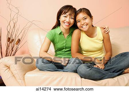 Mother and daughter, sitting on sofa, smiling View Large Photo Image Picture - Mother and daughter, sitting on sofa, smiling. Fotosearch