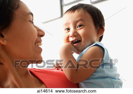 Mother carrying baby boy, boy with finger in mouth View Large Photo Image Picture - Mother carrying baby boy, boy with finger in mouth. Fotosearch