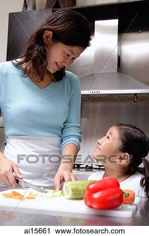 Mother cutting vegetables, daughter looking up at mother View Large Photo Image Stock Image - Mother cutting vegetables, daughter looking up at mother. Fotosearch
