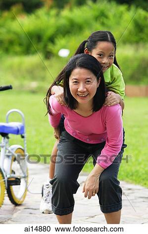 Mother giving daughter a piggyback, looking at camera View Large Photo Image Stock Image - Mother giving daughter a piggyback, looking at camera. Fotosearch