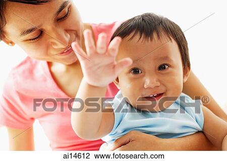 Stock Image - Mother holding baby boy, both smiling. Fotosearch