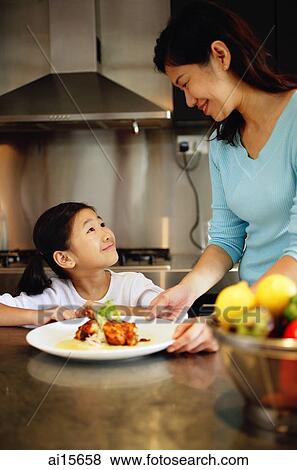 Mother holding plate and looking down at daughter View Large Photo Image Stock Photo - Mother holding plate and looking down at daughter. Fotosearch