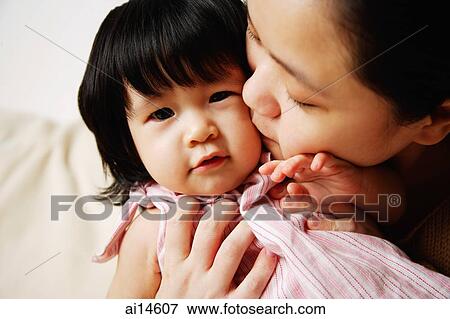 Stock Photo - Mother kissing baby girl on cheek. Fotosearch