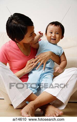 Mother sitting on floor, holding baby boy View Large Photo Image Stock Image - Mother sitting on floor, holding baby boy. Fotosearch