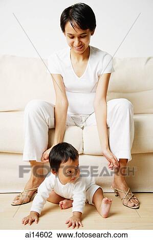 Mother sitting on sofa, baby boy sitting on floor View Large Photo Image Stock Image - Mother sitting on sofa, baby boy sitting on floor. Fotosearch