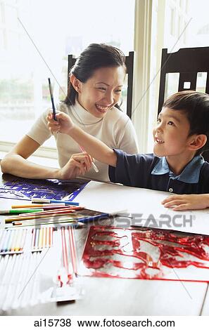 Mother sitting with son, colour pencils and drawing paper on the table, son holding pencil, looking up View Large Photo Image Stock Photo - Mother sitting with son, colour pencils and drawing paper on the table, son holding pencil, looking up. Fotosearch