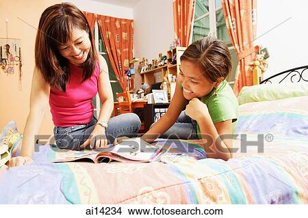 Mother with daughter, in bedroom, looking at magazine View Large Photo Image Picture - Mother with daughter, in bedroom, looking at magazine. Fotosearch
