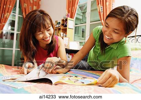 Mother with daughter, lying on bed, looking at magazine View Large Photo Image Stock Image - Mother with daughter, lying on bed, looking at magazine. Fotosearch