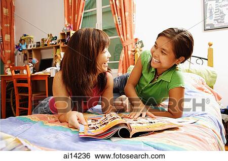 Mother with daughter, side by side on bed, looking at magazine View Large Photo Image Stock Photograph - Mother with daughter, side by side on bed, looking at magazine. Fotosearch