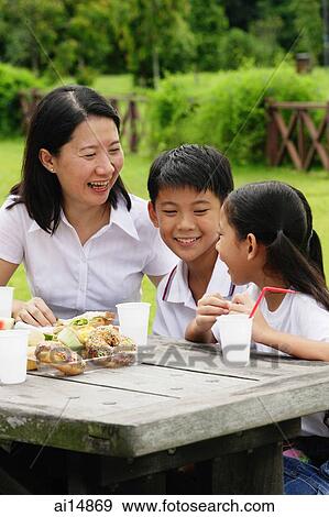 Mother with two children, sitting at picnic table View Large Photo Image Stock Photo - Mother with two children, sitting at picnic table. Fotosearch