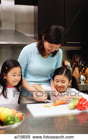 Stock Photo -  Mother with two daughters in kitchen. Fotosearch