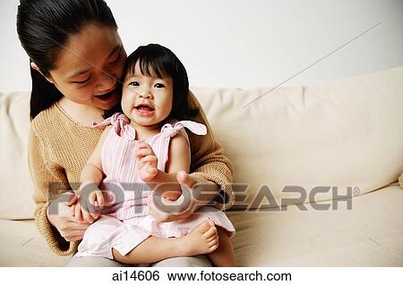 Stock Photograph - Mother with young daughter on sofa, bonding. Fotosearch